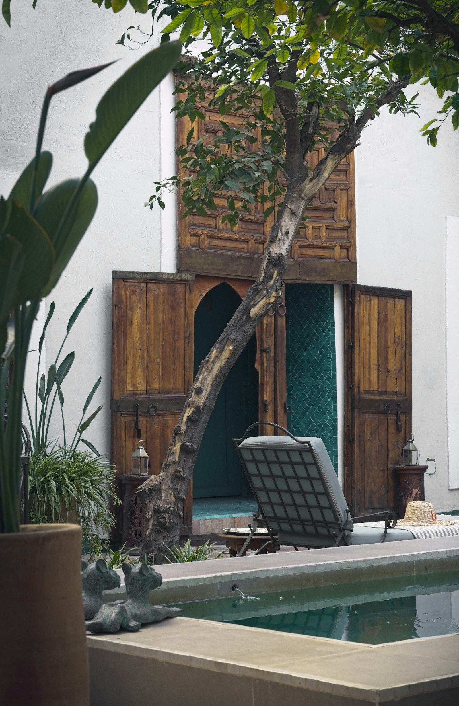 Naturally lit guesthouse courtyard with a small pool and timber doors